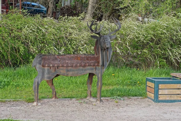 一个褐色铁锈的灰色旧金属钎子 街道上有一头鹿的身影 背景是绿色的植被 — 图库照片