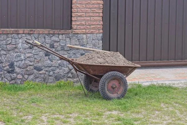 One Old Brown Metal Wheelbarrow Full Gray Sand Stands Green — Stockfoto