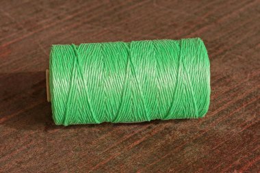 one large green coil of rope lies on a brown table