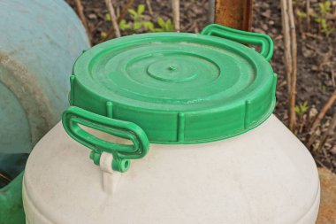 Yeşil kapaklı büyük beyaz plastik bir varil caddede duruyor.