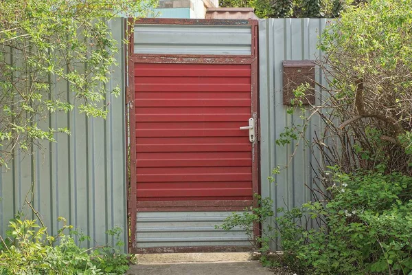 Parte Uma Parede Cerca Metal Cinza Porta Vermelha Coberto Com — Fotografia de Stock