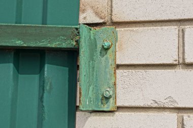 Açık havada beyaz tuğla bir duvara sabitlenmiş yeşil demir levha.