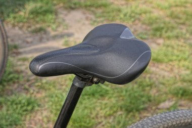 Sokakta bir spor bisikletinin çerçevesinde yeşil çimlerin arkasında bir siyah deri eyer.