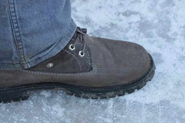 Один Коричневый Кожаный Ботинок Ноге Серых Джинсах Зимней Улице Белом — стоковое фото