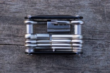 Çok araçlı bir metal bisiklet beyaz tuşlar ve tornavidalar tahta masa gri bir tahta üzerinde yatar