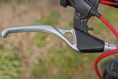 Beyaz metal el freni ve caddede kırmızı kablo olan siyah bir bisiklet gidonunun parçası.