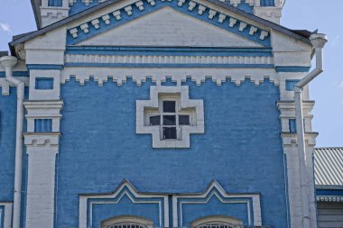 Eski bir binanın mavi beyaz tuğlalı duvarı ve sokakta küçük bir penceresi var.