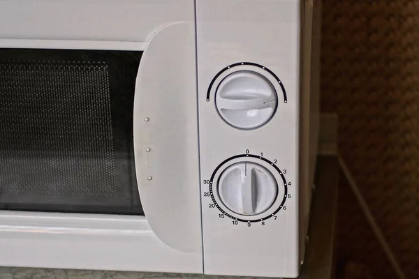 part of a microwave oven with two round plastic handles controls on a white panel