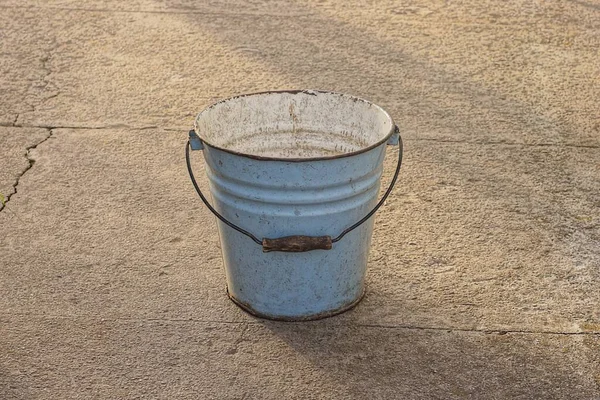 街上一个旧的肮脏的蓝色搪瓷桶铺在灰色的柏油上 — 图库照片