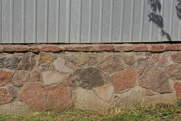 texture of brown stone foundation and gray metal in the wall of the fence on the street