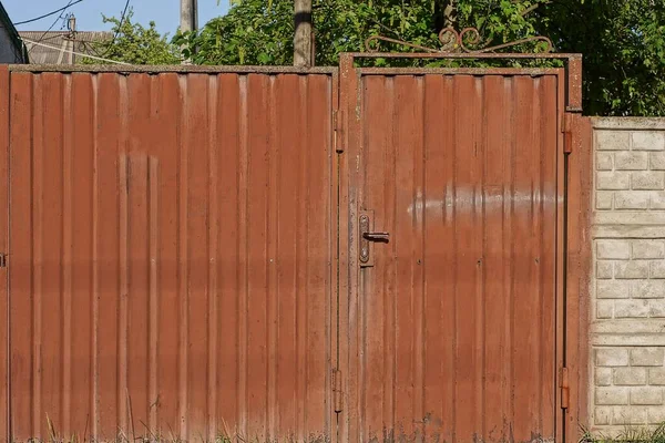 一扇紧闭在棕色金属上的铁门和乡间街道上的灰色混凝土围墙 — 图库照片