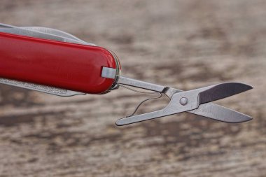 bir küçük gri metal makas kırmızı çoklu bir araç üzerinde ahşap bir masa üzerinde