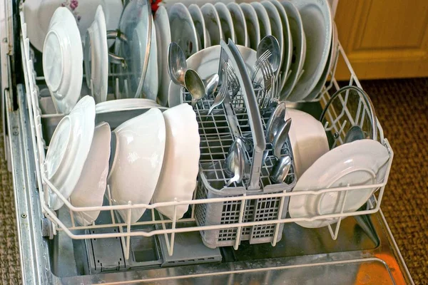 在厨房的洗碗机抽屉里用白色盘子 金属勺子和叉子做的一套厨房用具 — 图库照片