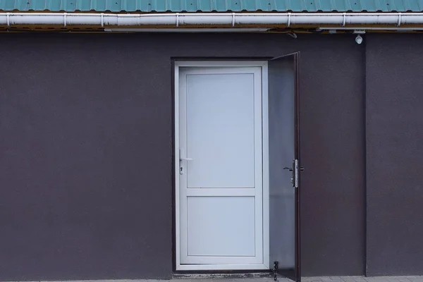 one white plastic door on a brown metal wall of a building on the street