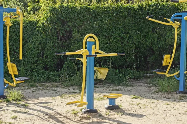 Bir Mavi Sarı Metal Spor Simülatörü Yeşil Çalıların Arkasında Duruyor — Stok fotoğraf