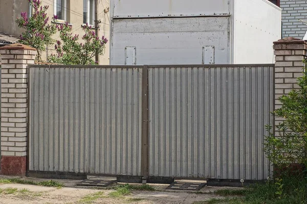 一个灰色的大铁门和街上的部分砖墙 — 图库照片