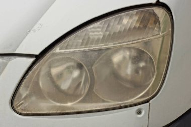 Beyaz araba metalinin üzerinde büyük gri bir ön cam far.