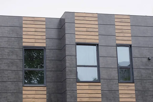 Siyah bir duvardan bir evin tavan arası ve caddelerde camları olan kahverengi ahşap tahtalar gri gökyüzüne karşı.