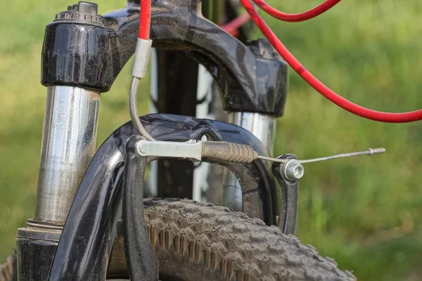 part of a sports bike from a metal fork spring on a black wheel on the street on a green background