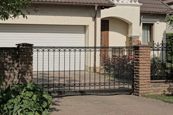 Siyah demir parmaklıklardan bir kapı ve caddelerde kahverengi tuğlalardan ve metalden bir çit