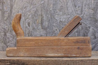 Eski bir alet kahverengi ahşap planör bir atölyede gri bir duvara karşı duruyor.