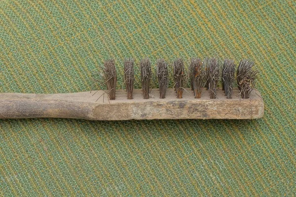 a tool from one old gray wooden brush for metal lies on a green table