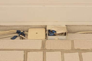 iki gri kare plastik kutu elektrik kabloları ve beyaz tuğla bir duvarda kablolar