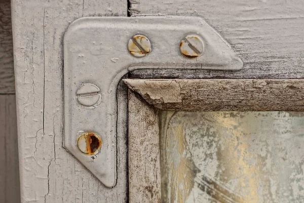one white metal corner on the wooden frame of an old window