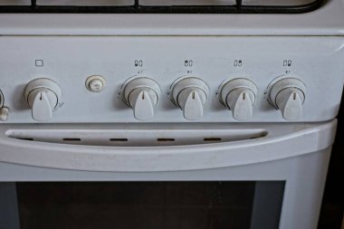 Mutfaktaki odadaki büyük beyaz metal gaz sobasının bir parçası.