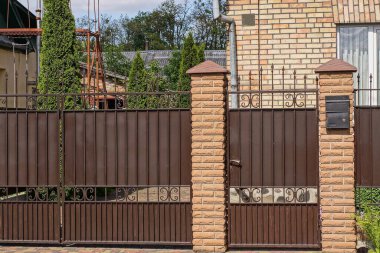  Kahverengi kapalı metal kapı, dövmeli demir desenli ve dışarıdaki tuğlalardan yapılmış bir duvarın kapısı.