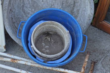 Gri asfalt üzerinde eski bir yığın kirli mavi leğen ve kovalar.