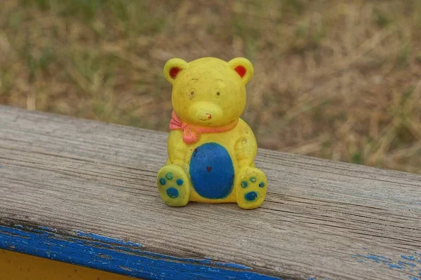 Один Пластик Желтый Синий Игрушечный Медвежонок Стоит Сером Деревянном Столе — стоковое фото