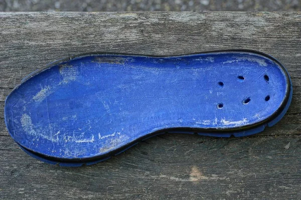 one blue old plastic sole shoe insole lies on a gray table