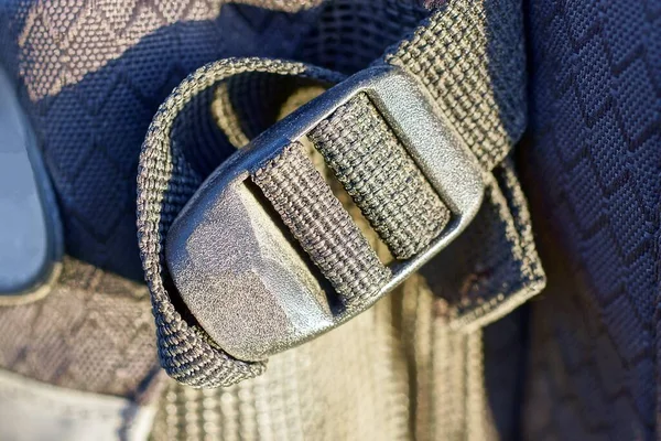 one closed black plastic carabiner latch on a fabric harness on a backpack