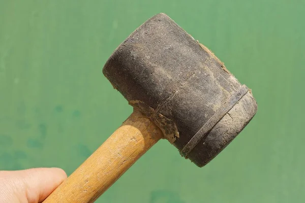 Hand Holds Black Plastic Mallet Hammer Brown Wooden Handle Green — 图库照片