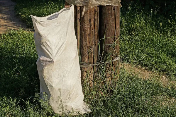 Een Witte Plastic Zak Met Vuilnisbakken Groen Gras Buurt Van — Stockfoto