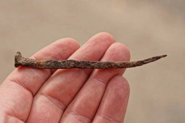 Fingers Hand Holds One Brown Rusty Iron Nail Gray Background — Zdjęcie stockowe