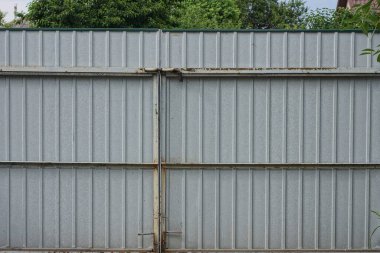 Kırsal bir sokakta gri kapalı bir metal kapı.