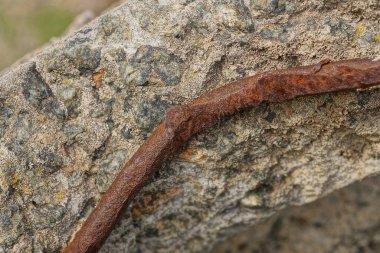 a piece of gray broken concrete wall with red rusty iron rod