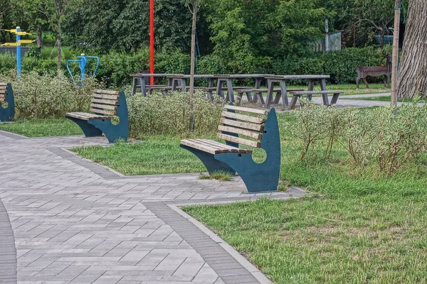 Two Empty Brown Wooden Bench Stand Green Grass Gray Sidewalk — Φωτογραφία Αρχείου