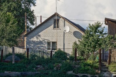 facade of one private house made of white brick behind a fence on the street against the sky