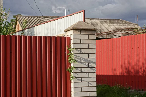 part of a private red metal and white brick wall fence in the street