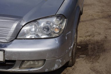 one white front glass headlight on a gray passenger car on the street