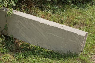 one big long gray concrete block stands on the ground and green grass outside
