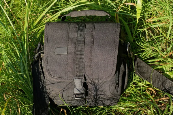 one black closed bag a wardrobe trunk made of fabric lies on the green grass in nature