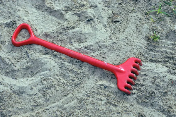 One Red Plastic Rake Lies Gray Sand Street — 图库照片