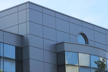 part of a large gray high building with windows on the street against the blue sky