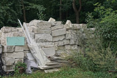 a large pile of white bricks on the street in green grass and green vegetation
