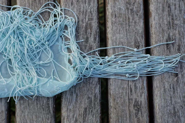 a piece of a blue crumpled handkerchief with laces lies on a gray wooden table board