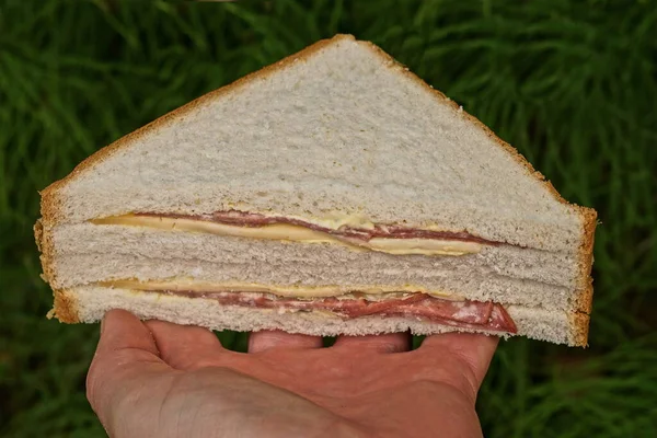 Hand Holds One Triangular Sandwich Made White Sausage Cheese Bread — Zdjęcie stockowe